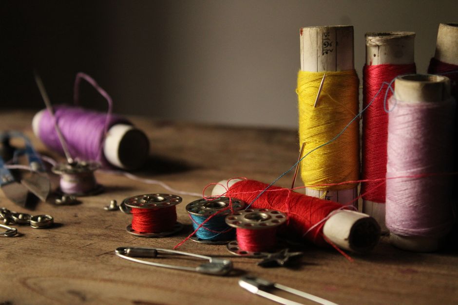 Vibrant sewing threads and spools on a rustic wooden table, ready for stitching projects.